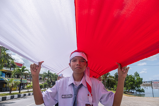 Студент держит флаг во время празднования  Дня независимости Индонезии