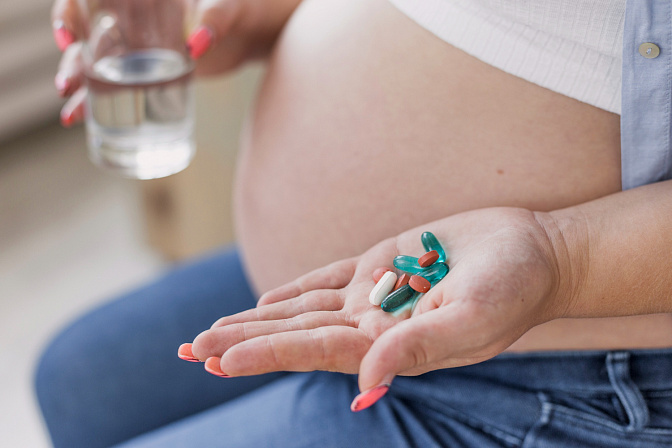 Беременная женщина, держащая таблетки